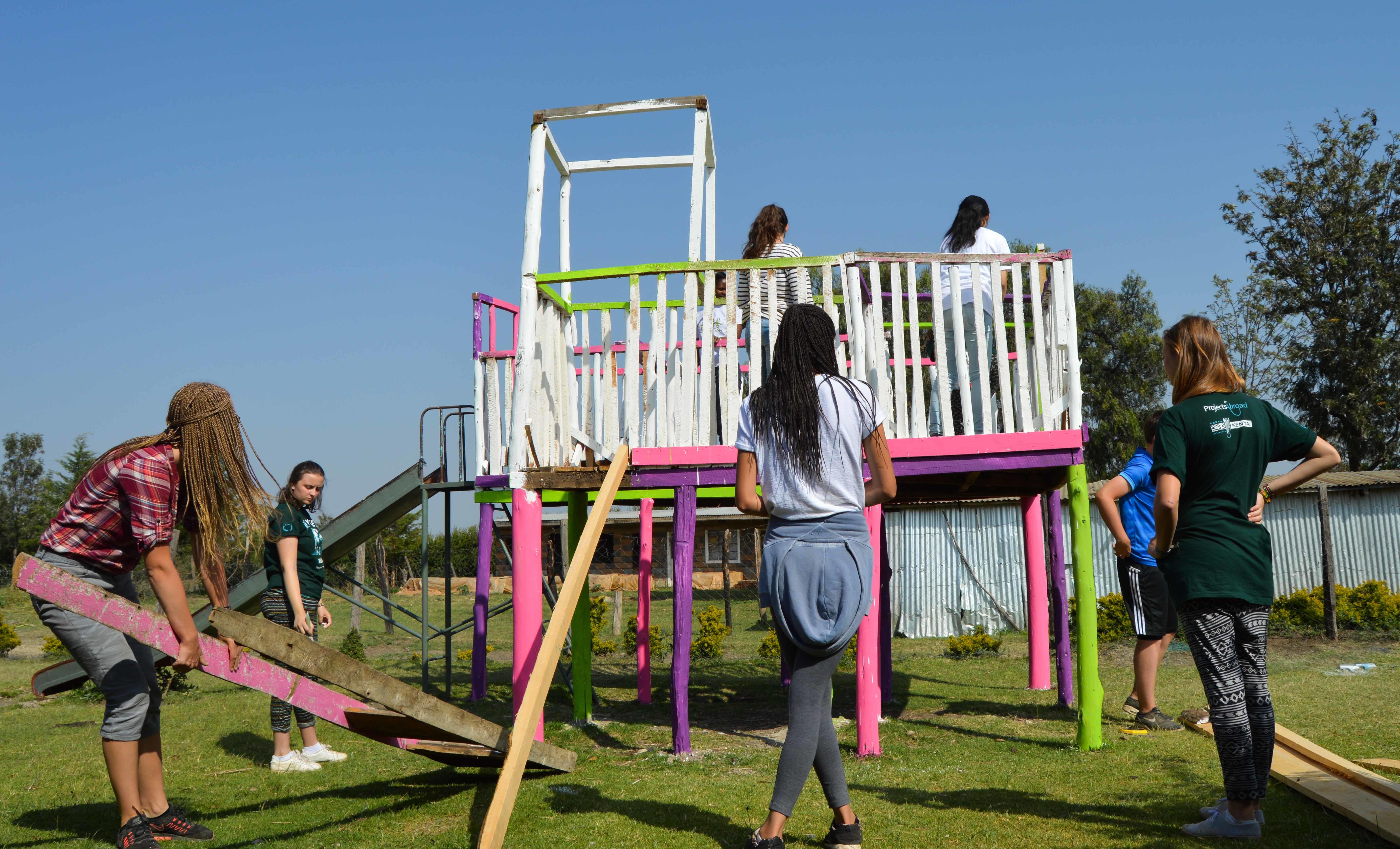 Durante su voluntariado para ayudar niños en Kenia, voluntarias ayudan a construir un patio de juegos. Voluntarios sociales en Kenia ayudan a crear un gimnasio para una escuela.